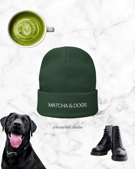 Green beanie with 'MATCHA & DOGS' text, black dog, green matcha cup, and black boots on a marble background.