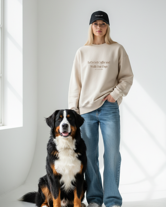 Person wearing a beige sweatshirt and black cap with a dog on a white background