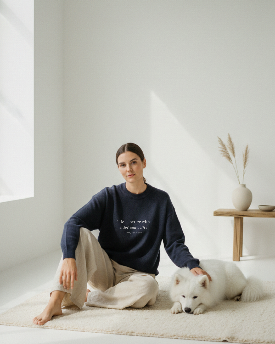 Woman sitting on a rug with a white dog in a bright room