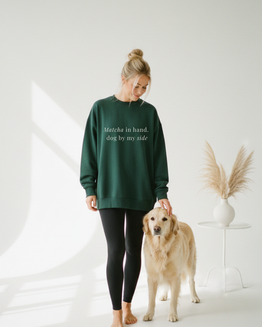 Woman wearing a green sweatshirt with text, standing next to a dog on a white background