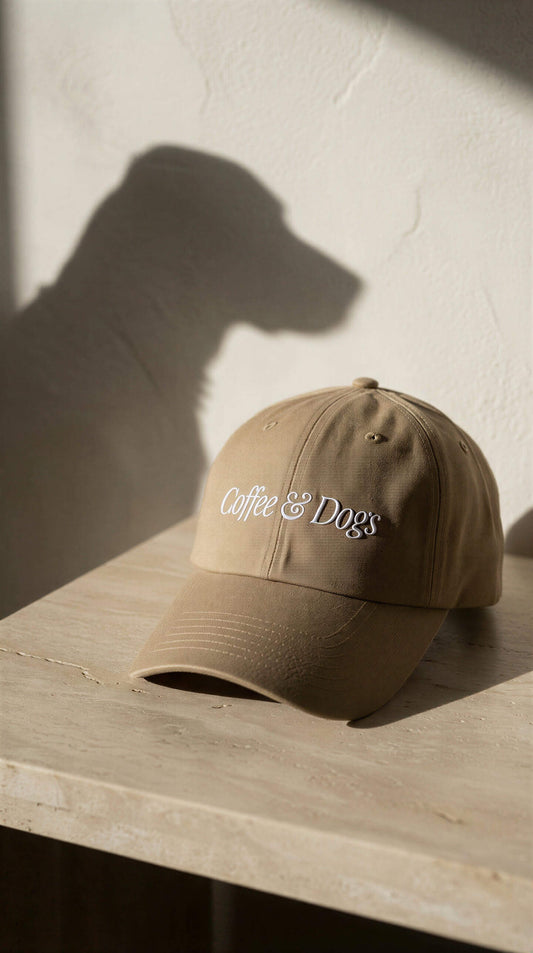 Brown cap with 'Coffee & Dogs' text on a wooden surface with a neutral background
