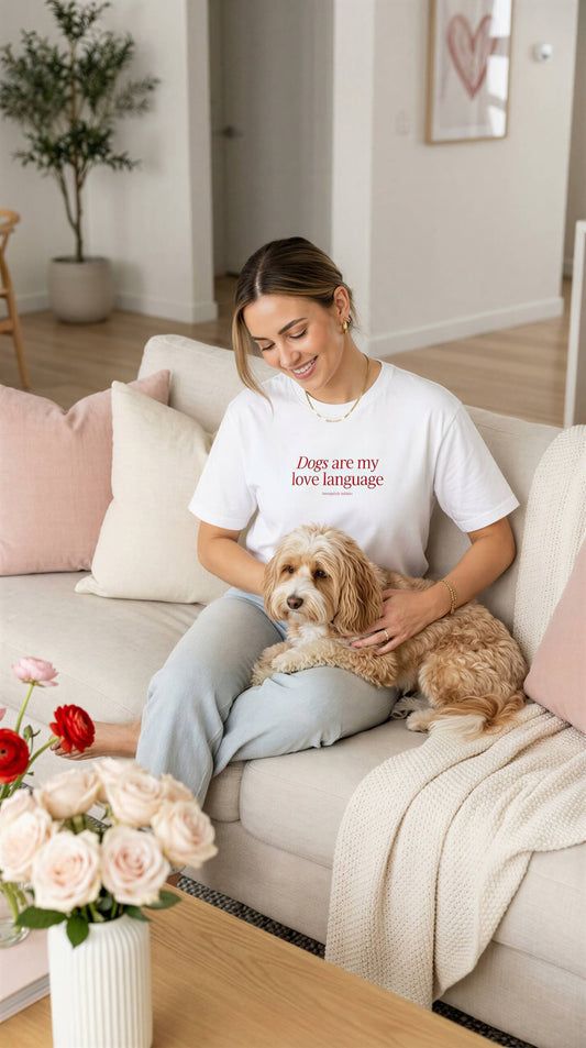 Woman sitting on a couch with a dog, wearing a t-shirt with text, in a cozy living room.