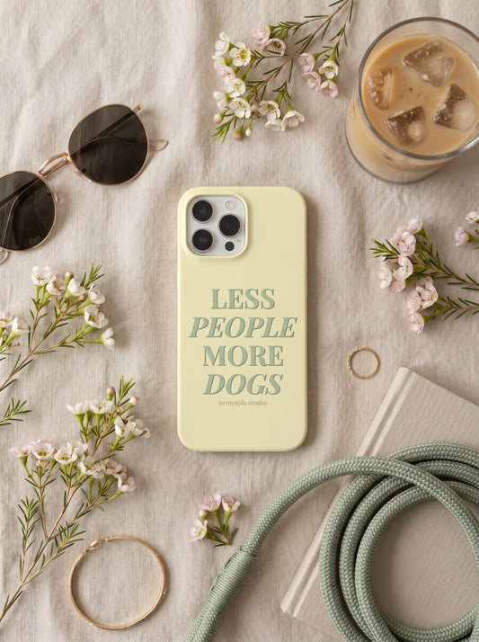 Minimal flat lay of the “Less People More Dogs” iPhone case styled with spring flowers, coffee, sunglasses, and neutral accessories.