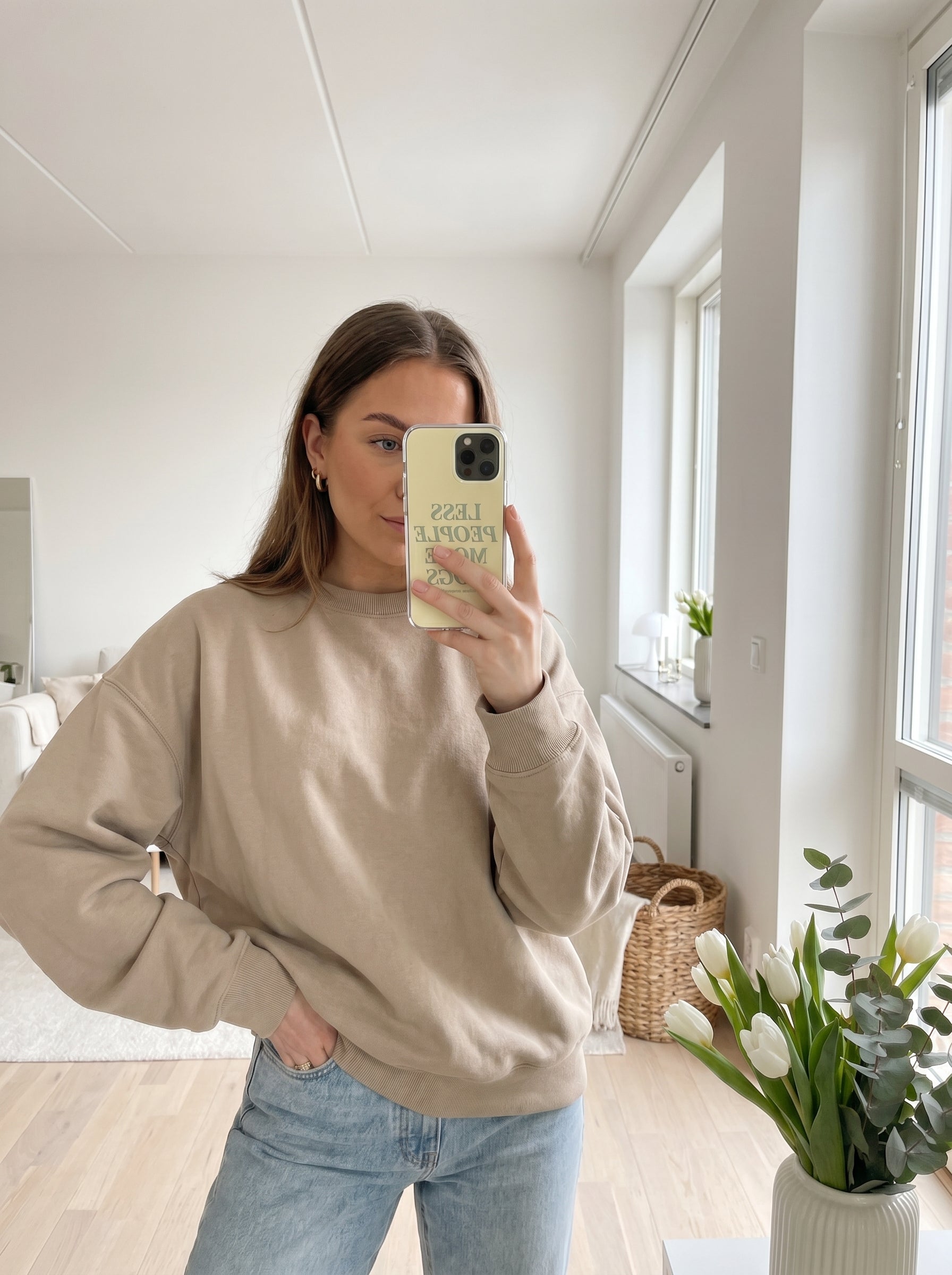 Mirror selfie featuring a neutral spring outfit and a pastel yellow “Less People More Dogs” iPhone case.