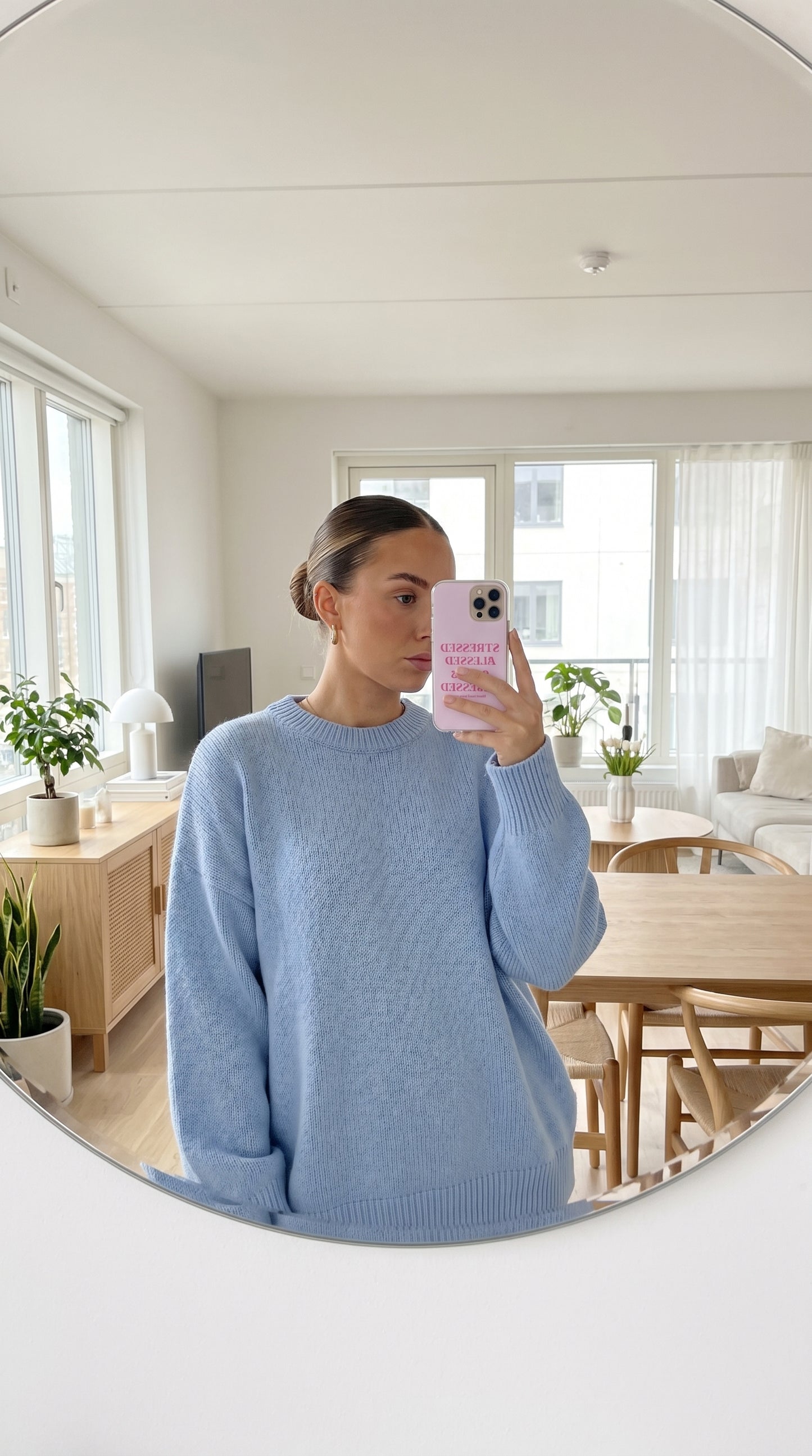 Mirror selfie featuring a pastel pink dog mom iPhone case in a bright minimalist apartment.