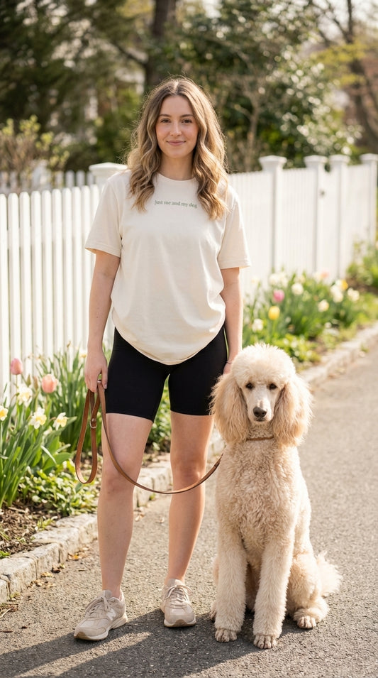 Woman walking a poodle on a leash in a park-like setting