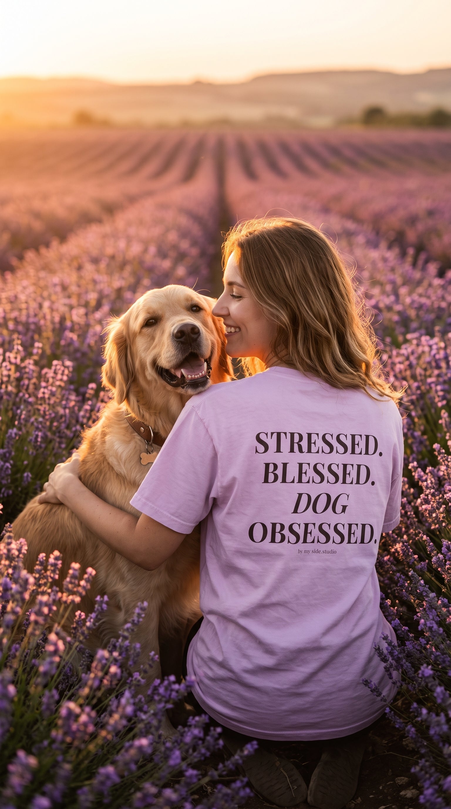 A woman in a lavender field hugging a golden retriever, wearing a light purple t-shirt with the text 'STRESSED, BLESSED, DOG OBSESSED.' printed on the back.