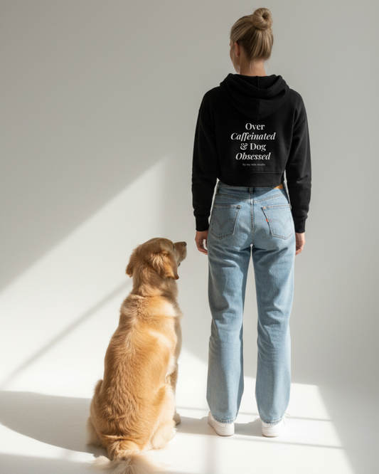 Person wearing a hoodie with text and a dog sitting on the floor in a well-lit room. Over Caffeinated & Dog Obsessed - Hoodie